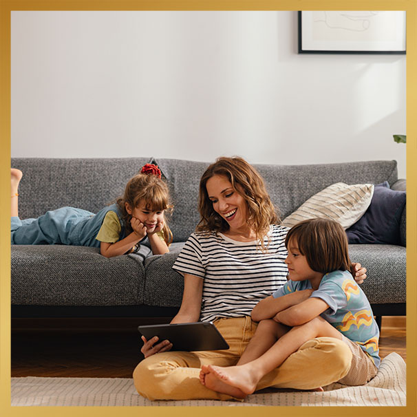 woman with her kids sitting on the floor and using digital tablet