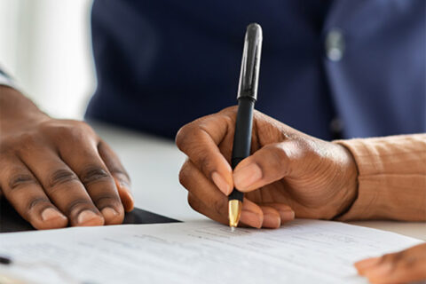 Person signing paperwork during assisted living consultation.