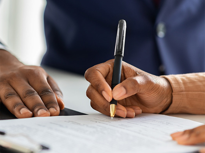 Person signing paperwork during assisted living consultation.
